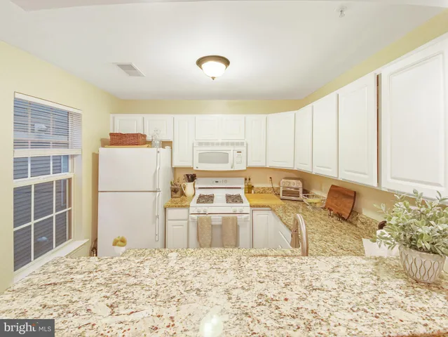 a living room with stainless steel appliances furniture a chandelier and a kitchen view