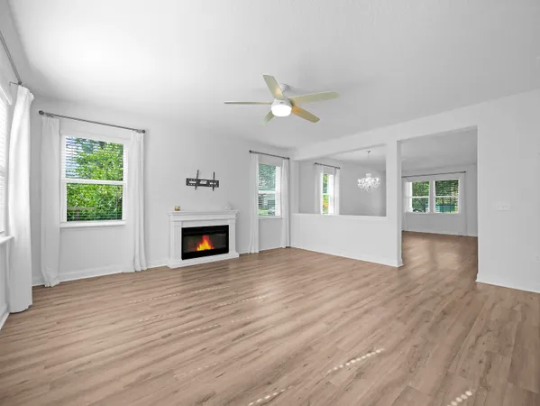 an empty room with a ceiling fan and kitchen view