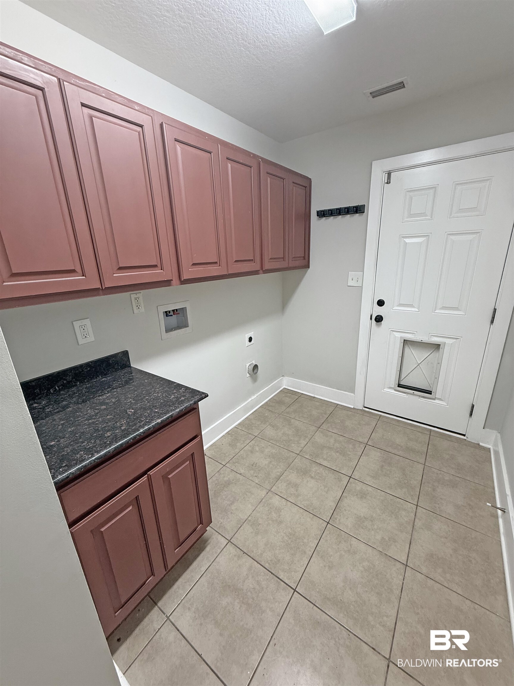 22023 Garland Loop Silverhill, AL 36576 - Photo 28 of 33 Laundry room with cabinet space, light tile patterned floors, electric dryer hookup, washer hookup, and a textured ceiling