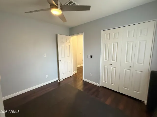 an empty room with wooden floor and windows with curtains