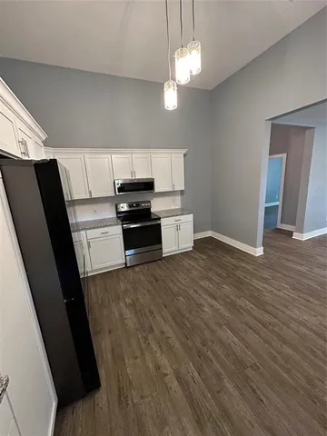 a kitchen with granite countertop a refrigerator and a stove top oven