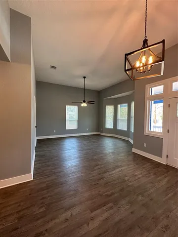 an empty room with wooden floor chandelier and entryway