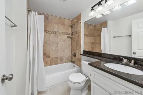 a bathroom with a granite countertop sink toilet a shower and a mirror