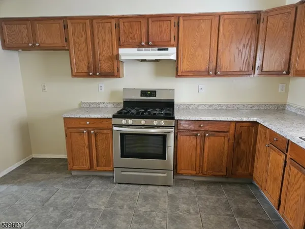 a kitchen with granite countertop a stove top oven microwave and cabinets