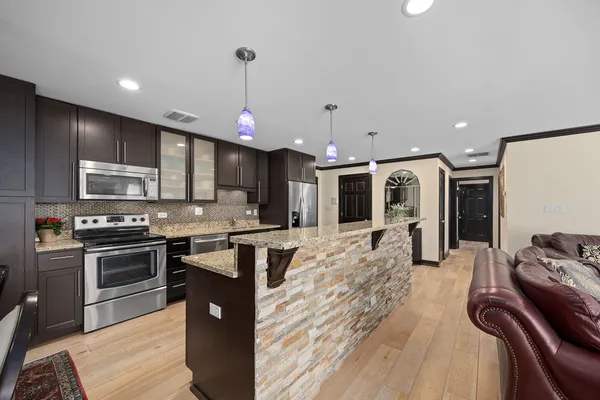 a kitchen with stainless steel appliances granite countertop a stove top oven a sink dishwasher a dining table and chairs with wooden floor