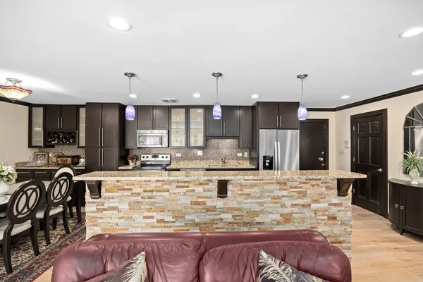 a view of a kitchen with kitchen island granite countertop a large counter top cabinets appliances and a ceiling fan