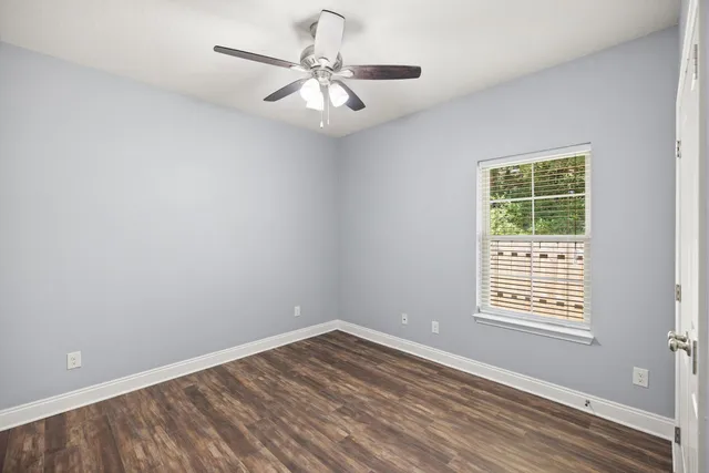 a view of an empty room with wooden floor and a window