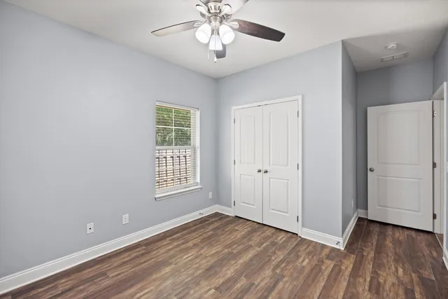a view of an empty room with a window and wooden floor