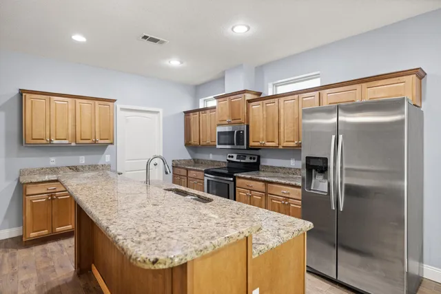 a kitchen with kitchen island granite countertop a sink stove and refrigerator
