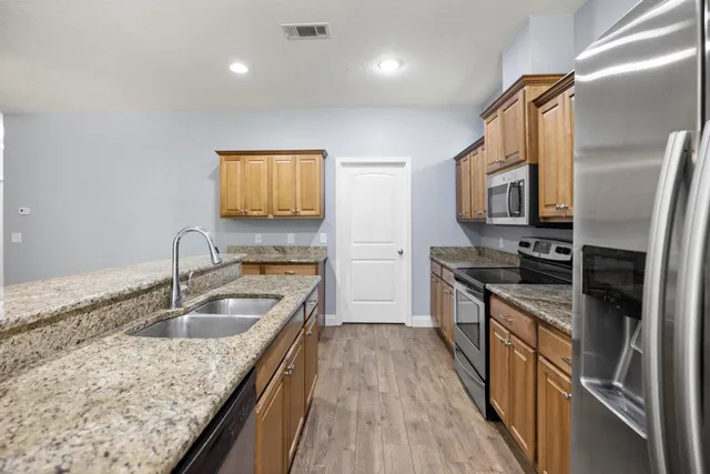 a kitchen with granite countertop a sink stove and refrigerator
