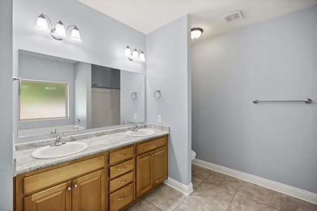 a bathroom with a granite countertop sink double vanity and a mirror