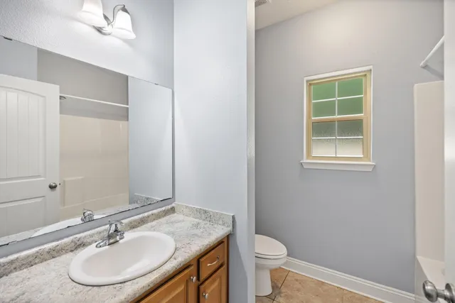 a bathroom with a granite countertop sink toilet a mirror and a window