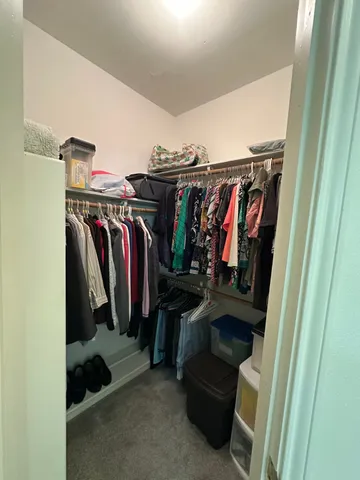 a view of walk in closet with clothes and shoes