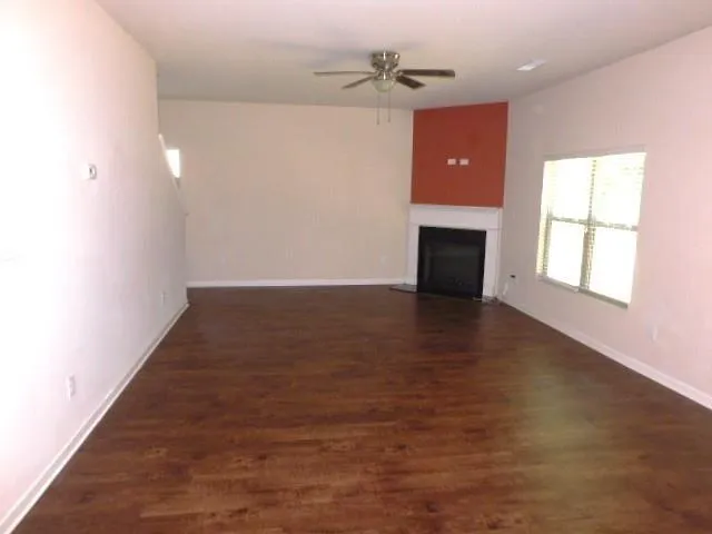 an empty room with wooden floor fireplace and windows