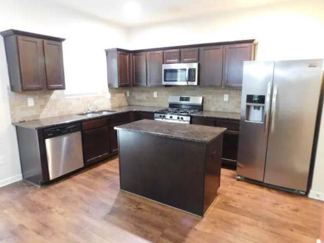 a kitchen with stainless steel appliances granite countertop a refrigerator a stove top oven a sink and dishwasher