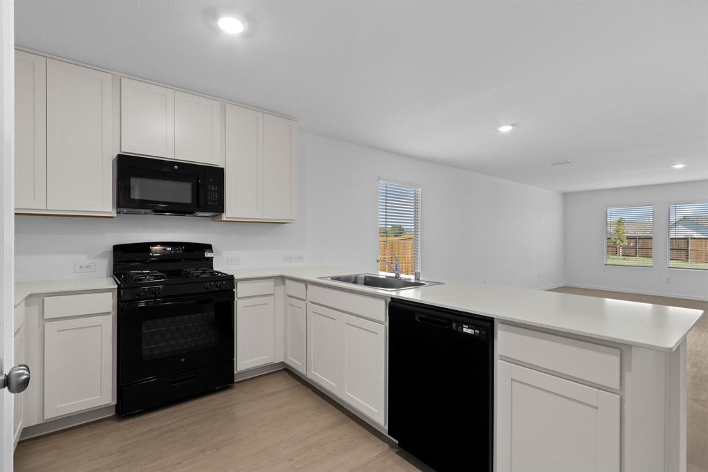 11333 Rodeo Drive Providence Village, TX 76227 - Photo 13 of 39 a kitchen with granite countertop white cabinets and black appliances