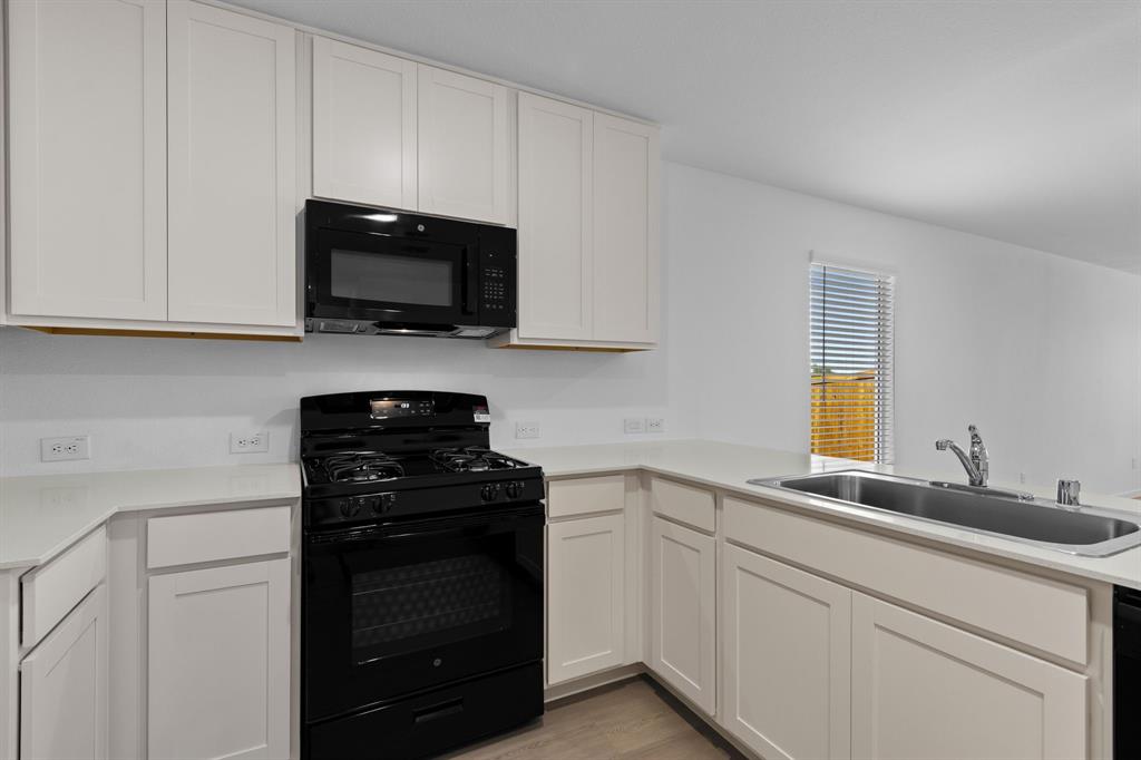 11333 Rodeo Drive Providence Village, TX 76227 - Photo 14 of 39 a kitchen with white cabinets and black appliances