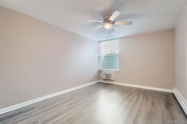 an empty room with wooden floor fan and windows