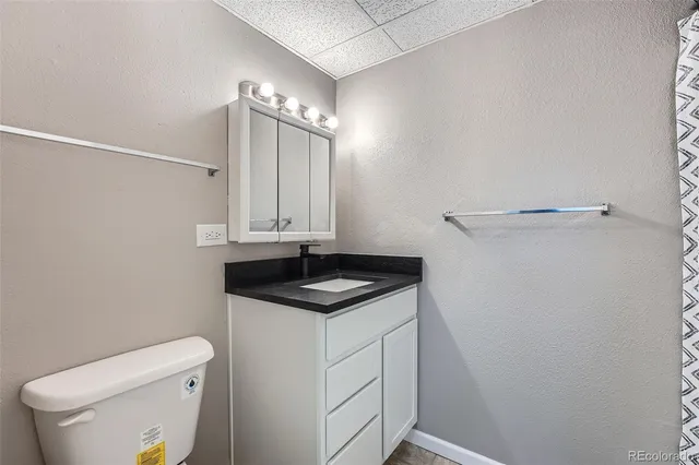 a bathroom with a granite countertop sink and a toilet