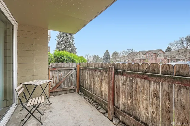 a view of a balcony with chairs and wooden fence