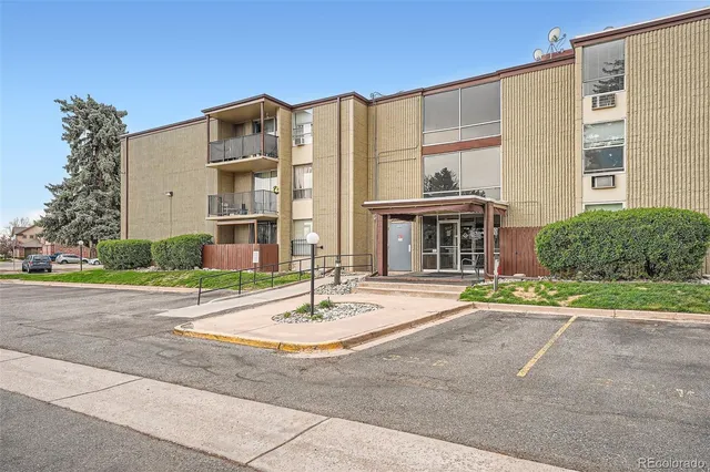 a front view of a building with a garden and plants