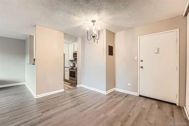 an empty room with wooden floor chandelier and entryway