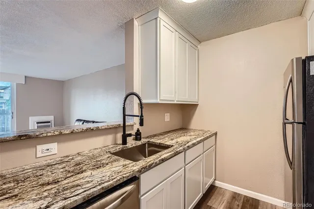 a kitchen with granite countertop a sink stove and refrigerator