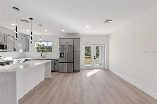 a large white kitchen with kitchen island a sink a stove a refrigerator and white cabinets