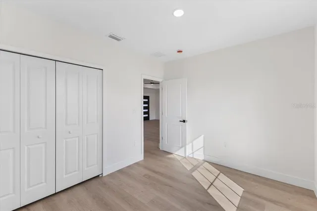 an empty room with wooden floor and window