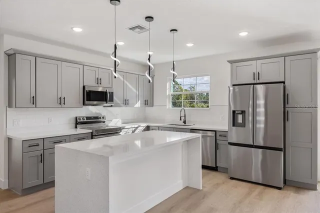 a kitchen with stainless steel appliances a refrigerator sink and microwave