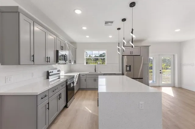 a large kitchen with stainless steel appliances kitchen island granite countertop a sink and cabinets