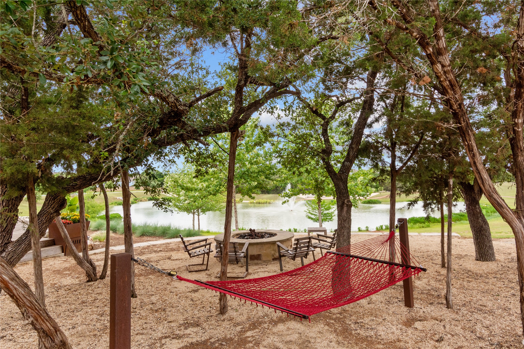 1108 Mallow Road Leander, TX 78641 - Photo 24 of 30 Mature trees frame a stone fire pit area overlooking the calm neighborhood pond.