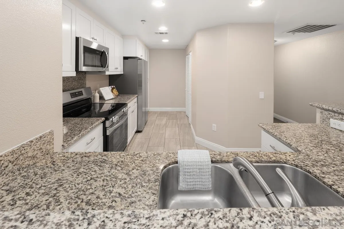 9229 Regents Road, Unit L124 La Jolla, CA 92037 - Photo 6 of 46 a kitchen with stainless steel appliances granite countertop a sink a stove top oven a granite counter space and cabinets
