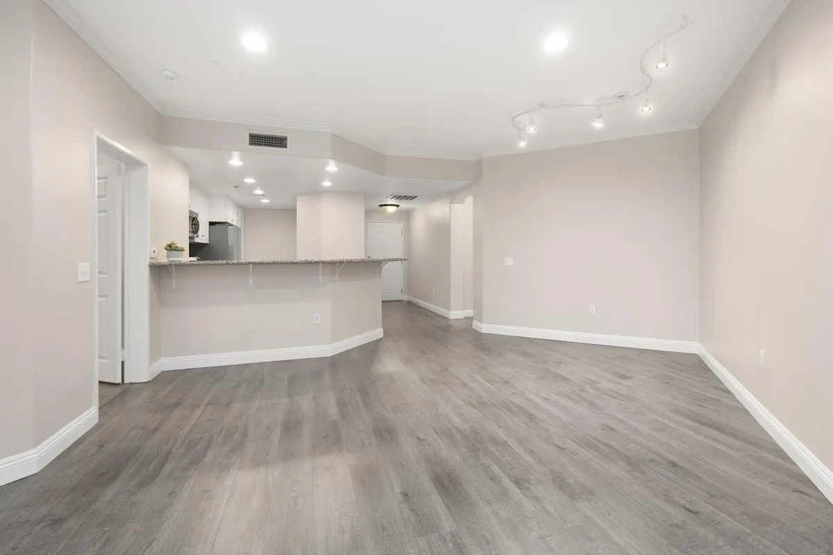 9229 Regents Road, Unit L124 La Jolla, CA 92037 - Photo 7 of 46 an empty room with wooden floor and kitchen view