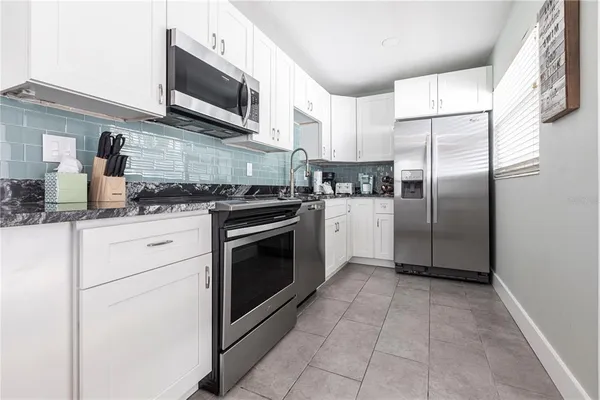 a kitchen with stainless steel appliances granite countertop a stove a refrigerator and a microwave