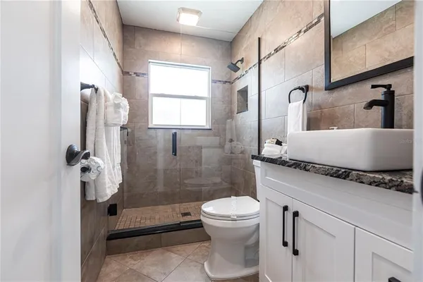 a bathroom with a granite countertop sink a toilet and shower