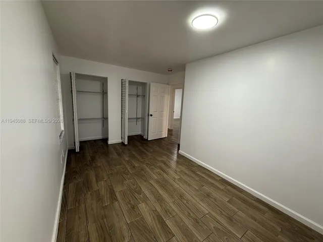 an empty room with wooden floor and closet