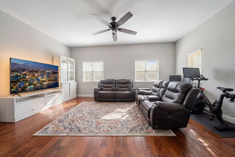 a living room with furniture flat screen tv and wooden floor