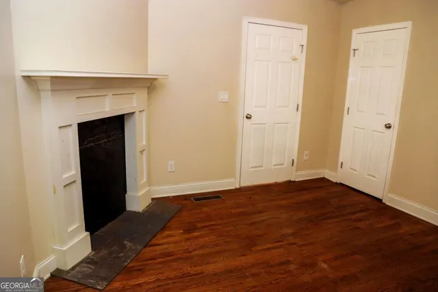 a view of an empty room with wooden floor and a fireplace