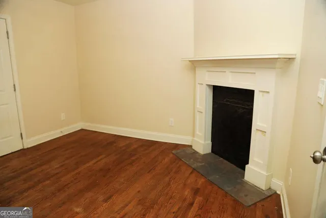 a view of an empty room with wooden floor and a fireplace