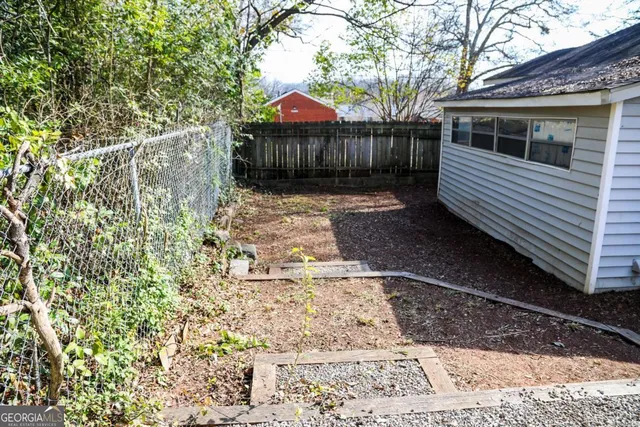 a view of a small yard with wooden fence and a bench