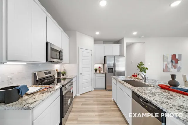 a kitchen with stainless steel appliances granite countertop lots of counter top space a sink a stove a refrigerator a counter top space and cabinets