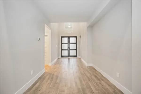 a view of an empty room with wooden floor and stairs