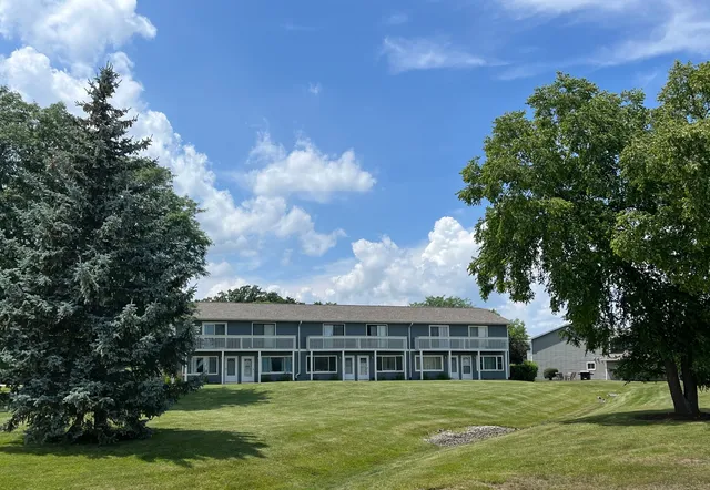 a view of a house next to a big yard and large trees