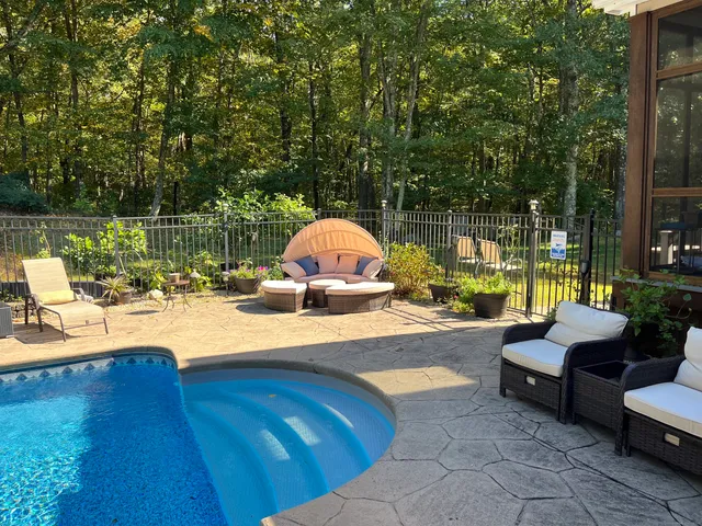 a view of pool with lawn chairs and wooden fence
