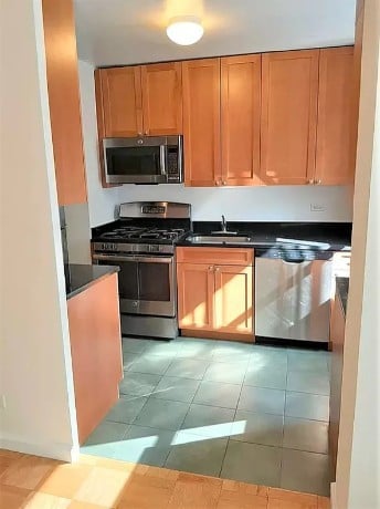 a kitchen with stainless steel appliances granite countertop a stove a sink and a microwave