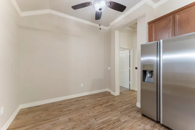 an empty room with a chandelier fan and windows