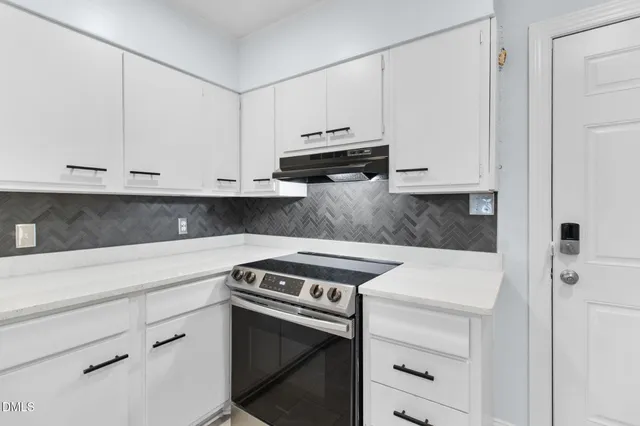 a kitchen with granite countertop white cabinets and stainless steel appliances