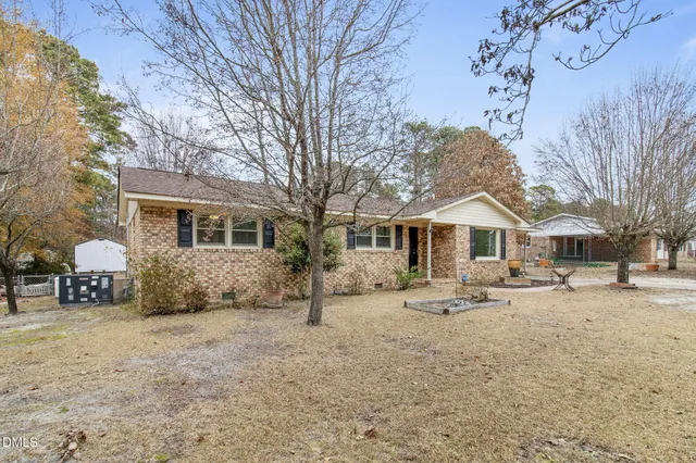 a front view of a house with a dirt yard and a large tree