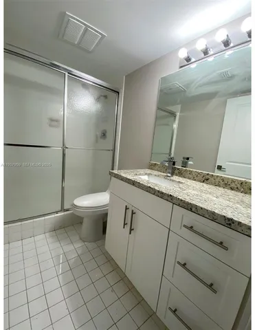 a bathroom with a granite countertop sink a toilet a mirror and shower